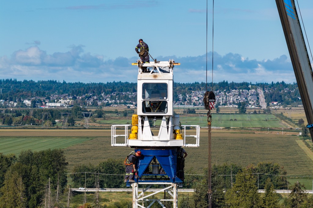 Crew assembling the crane cab and jib at the top of the tower at Clayton Crest in West Clayton, Surrey