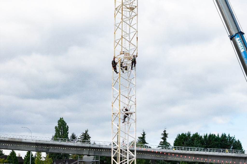 Three crew members on the white crane tower at Clayton Crest in West Clayton, Surrey