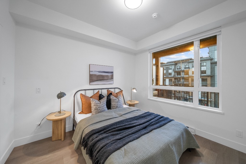 Bedroom at The Commons condos in Willoughby, Langley, with a large window overlooking the neighbourhood